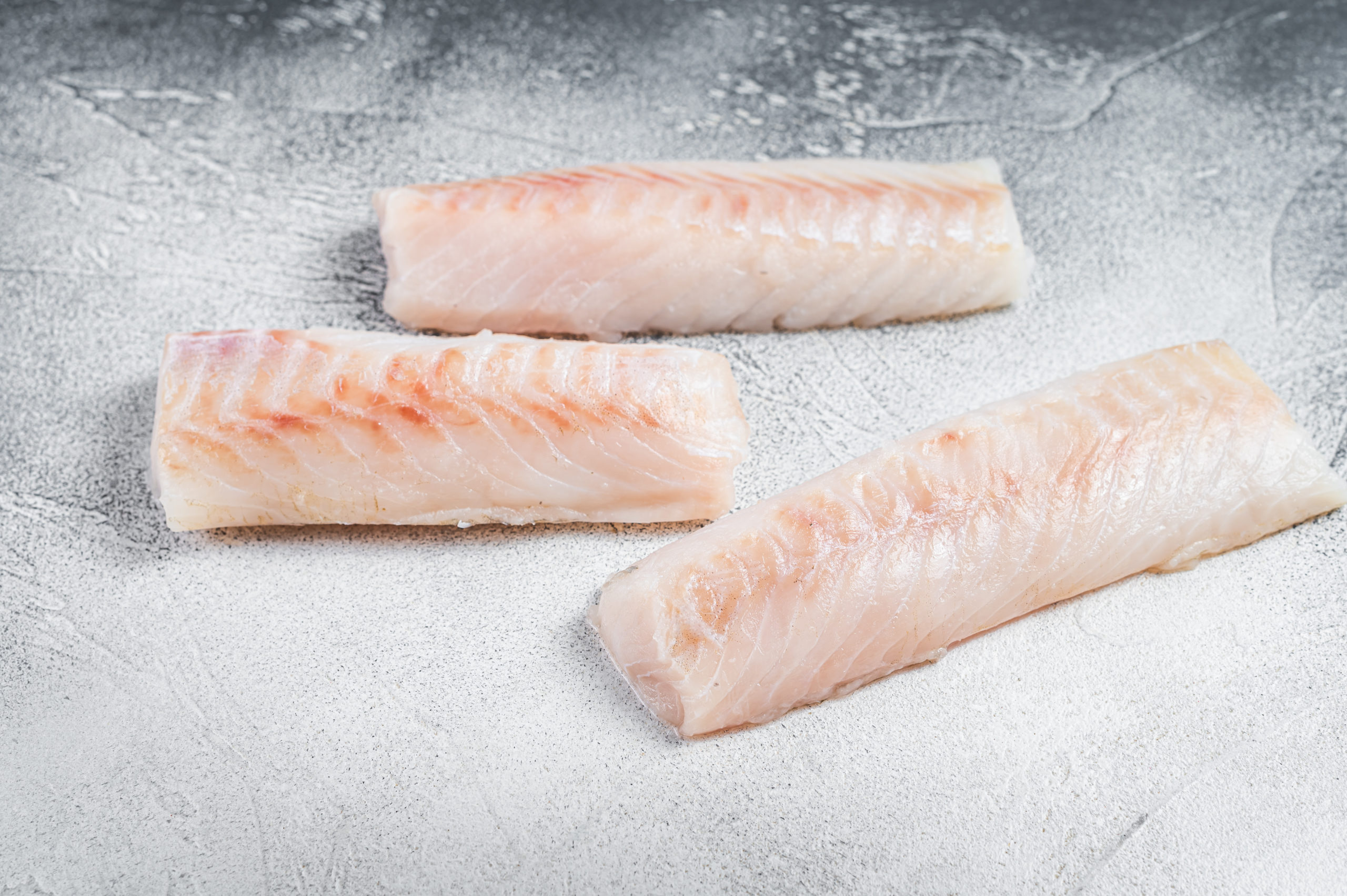Raw Norwegian cod fish fillet on kitchen table. White background
